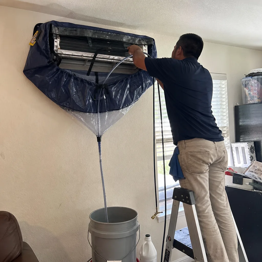 Technician performing professional HVAC ductless mini-split air conditioning system cleaning